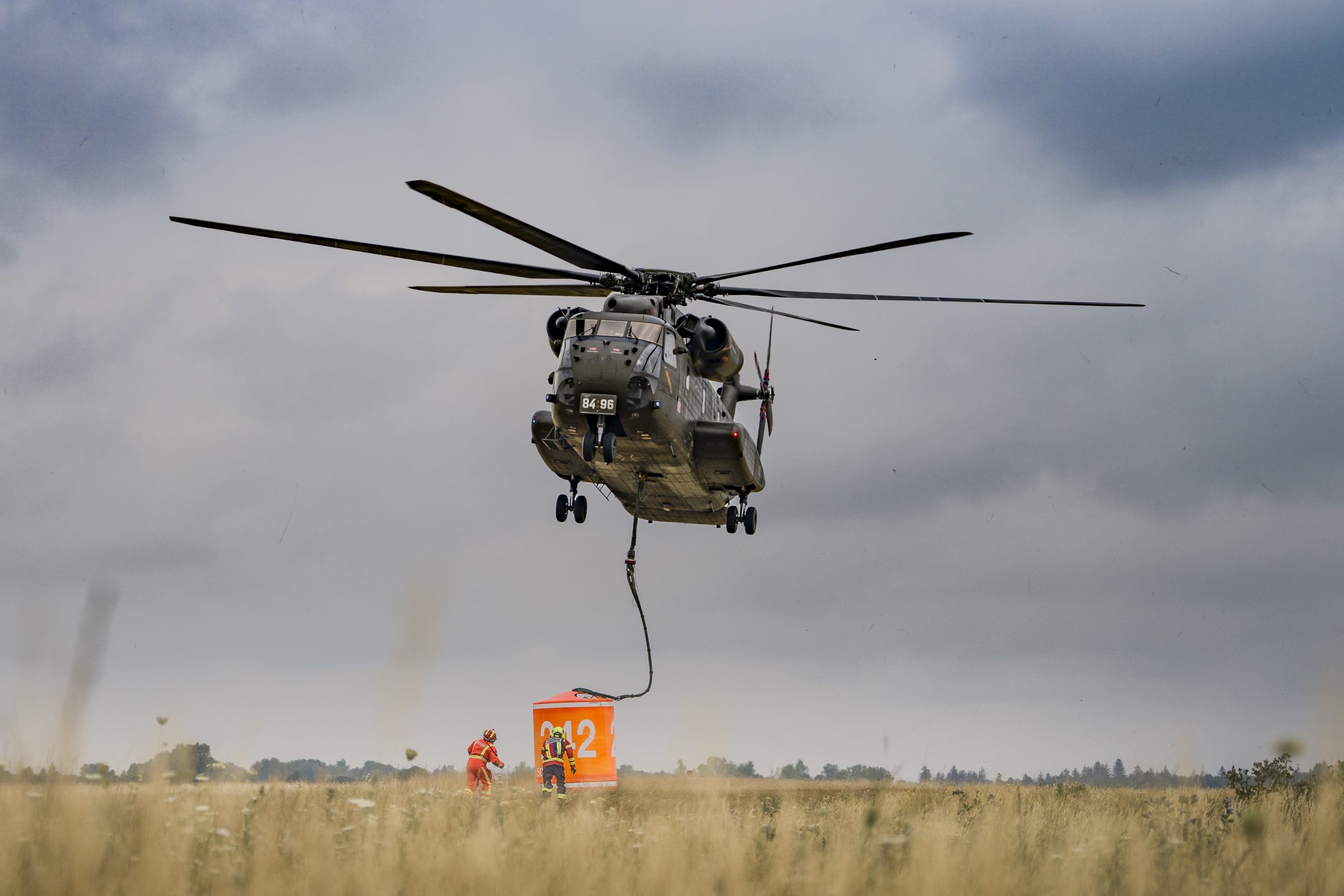 Ein Helikopter der Flughelfer schwebt und zieht einen Wassertank in die Luft