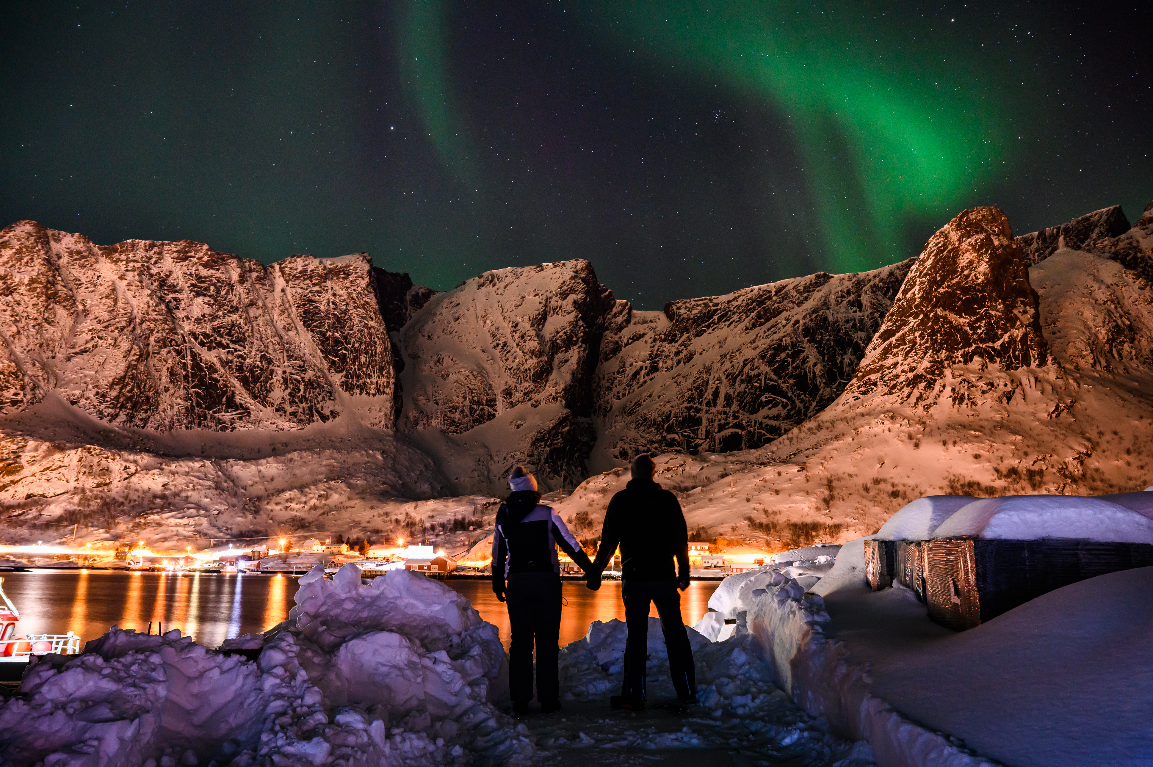 Ein Paar hält Händchen, während im Hintergrund die Polarlichter scheinen. 
